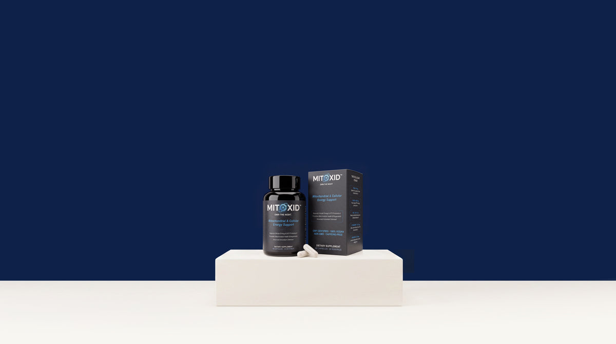 Mitoxid bottle and carton with two capsules on a white plinth against a midnight blue wall