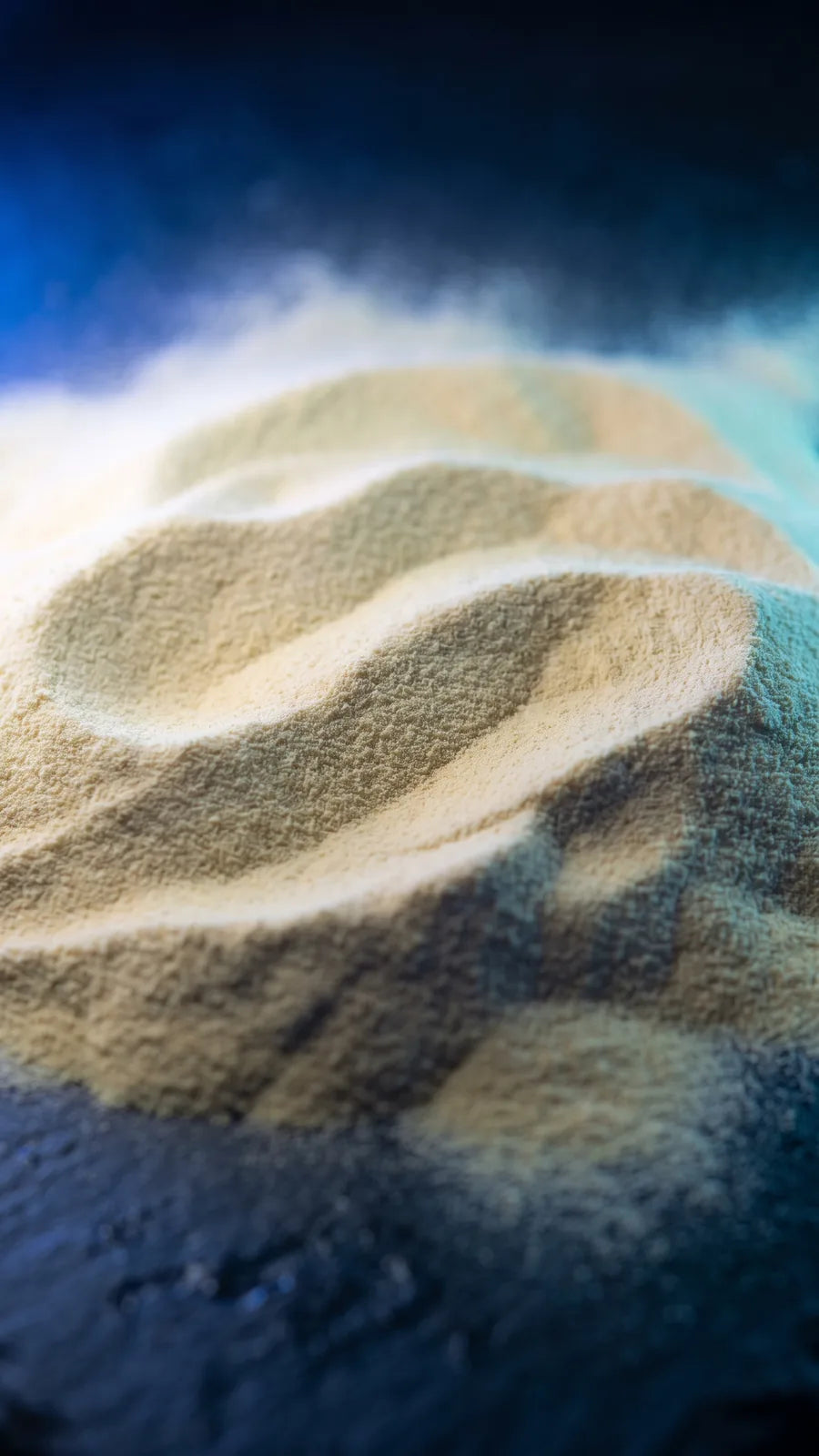 Macro of pale straw-yellow powder in low dunes on dark slate