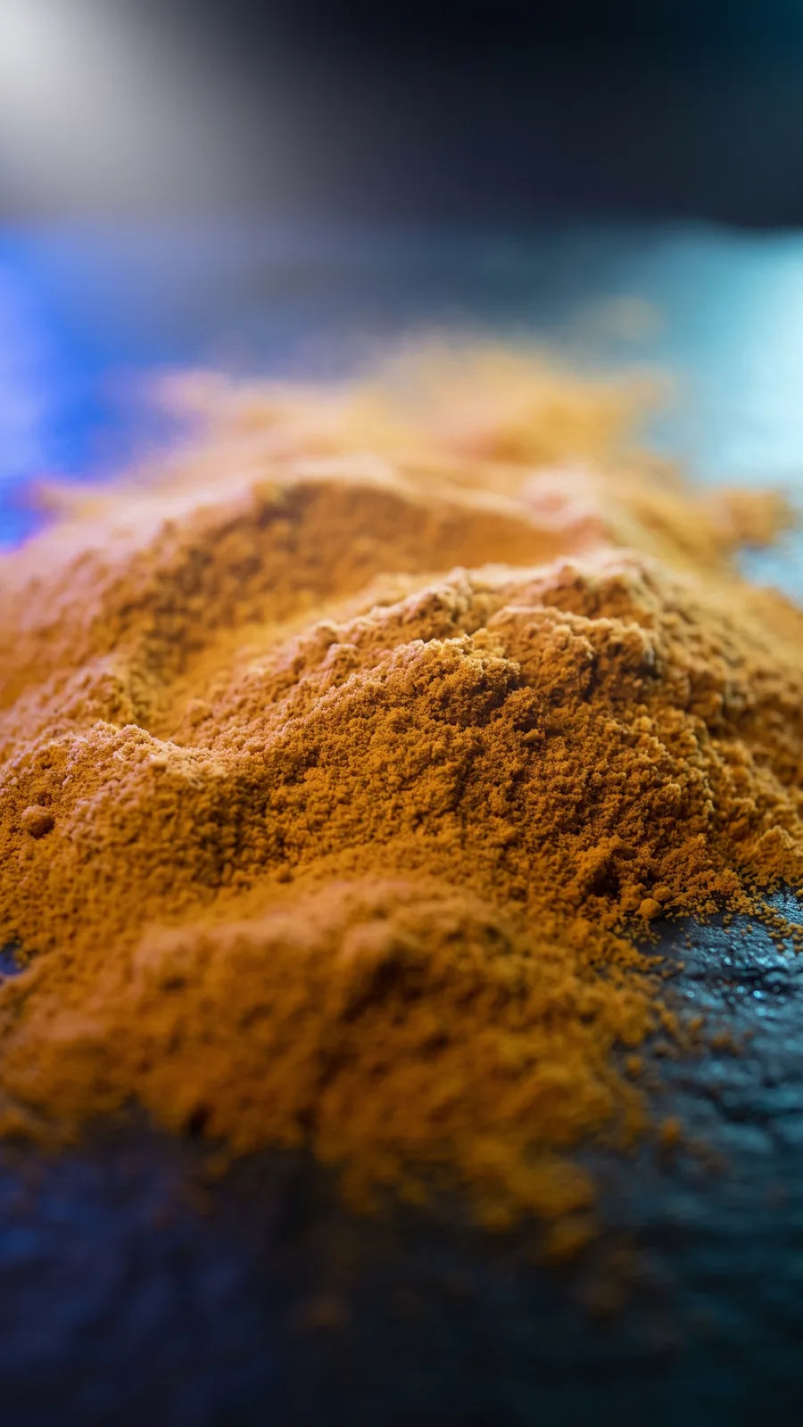 Macro of deep golden-orange powder against cold blue shadow