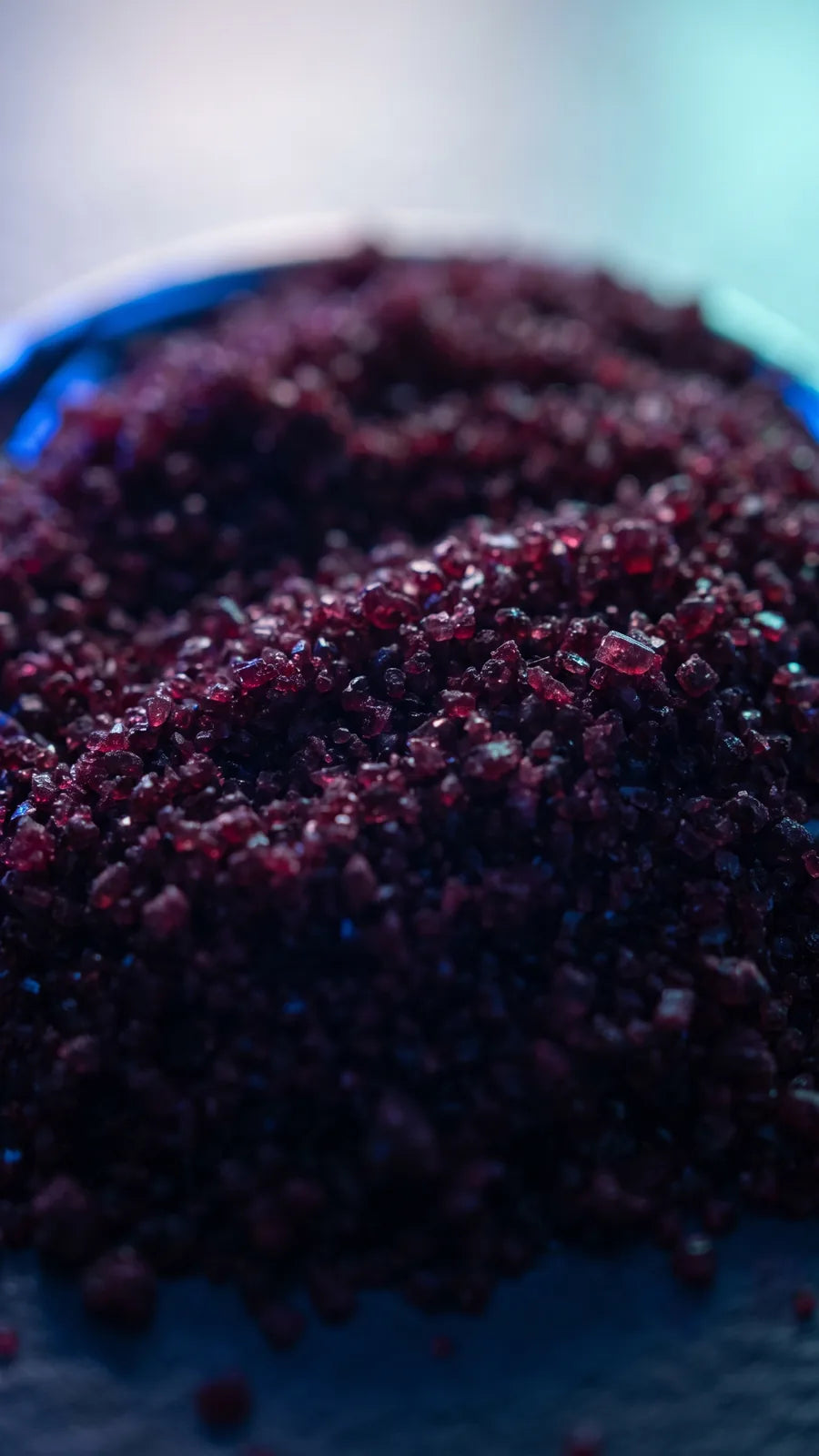 Macro of deep burgundy crystalline powder on dark slate
