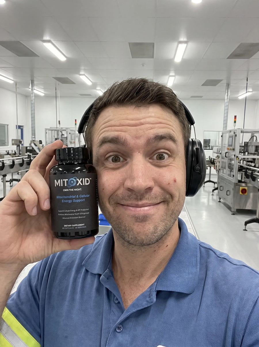 Customer photo: a factory line worker in ear defenders holding the Mitoxid bottle